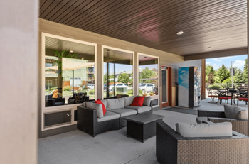 A modern outdoor seating area with a wooden ceiling and large windows.
